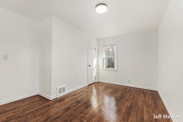 spare room with hardwood / wood-style flooring, baseboards, and visible vents