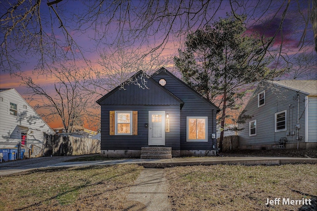 bungalow-style home featuring board and batten siding and fence