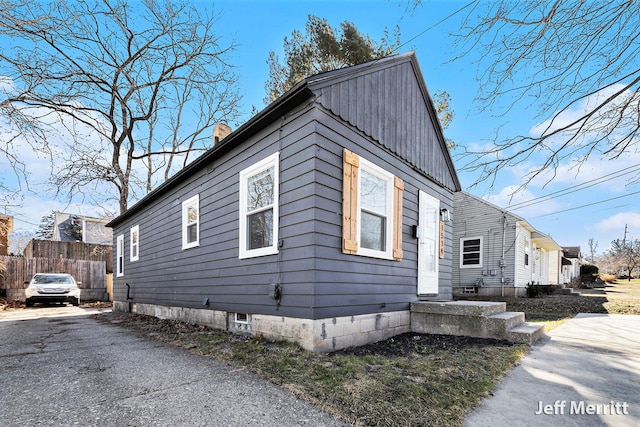 view of property exterior featuring board and batten siding, a chimney, and fence