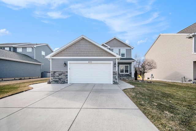 craftsman house with a front yard, an attached garage, stone siding, and driveway