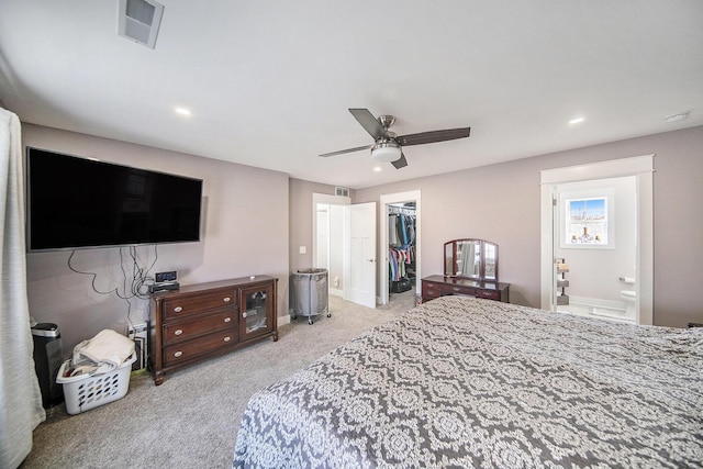 carpeted bedroom featuring visible vents, connected bathroom, a walk in closet, baseboards, and a closet