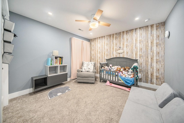 bedroom with carpet flooring, visible vents, wood walls, and ceiling fan