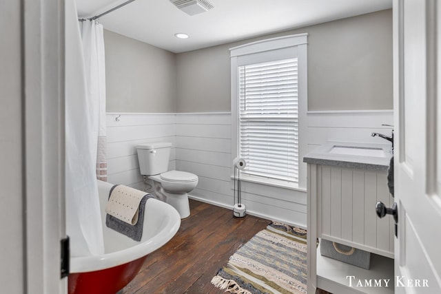 bathroom featuring visible vents, hardwood / wood-style flooring, a sink, a wainscoted wall, and toilet