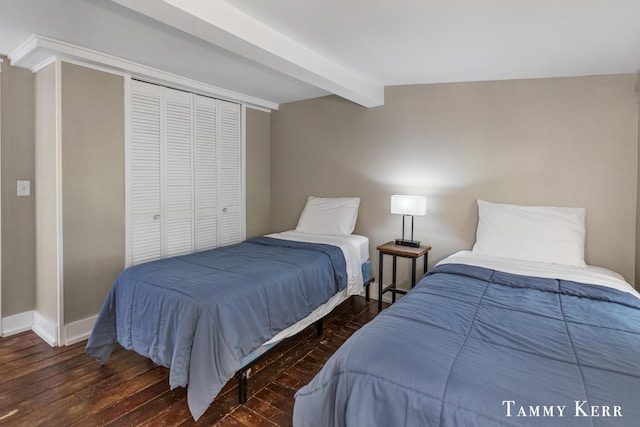 bedroom with a closet, baseboards, beam ceiling, and hardwood / wood-style flooring