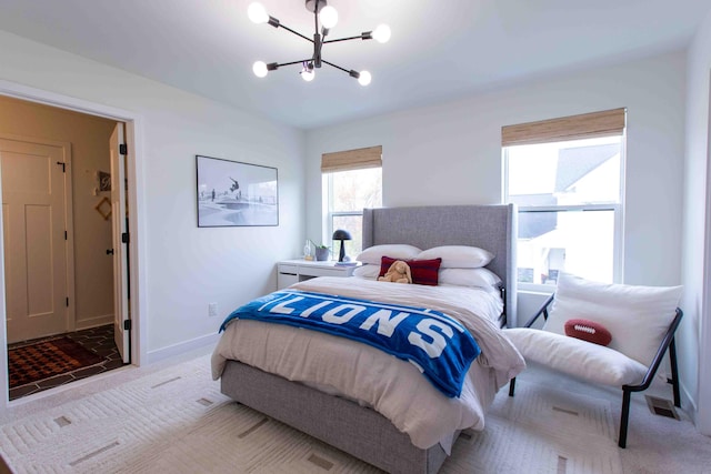 carpeted bedroom featuring a notable chandelier and baseboards