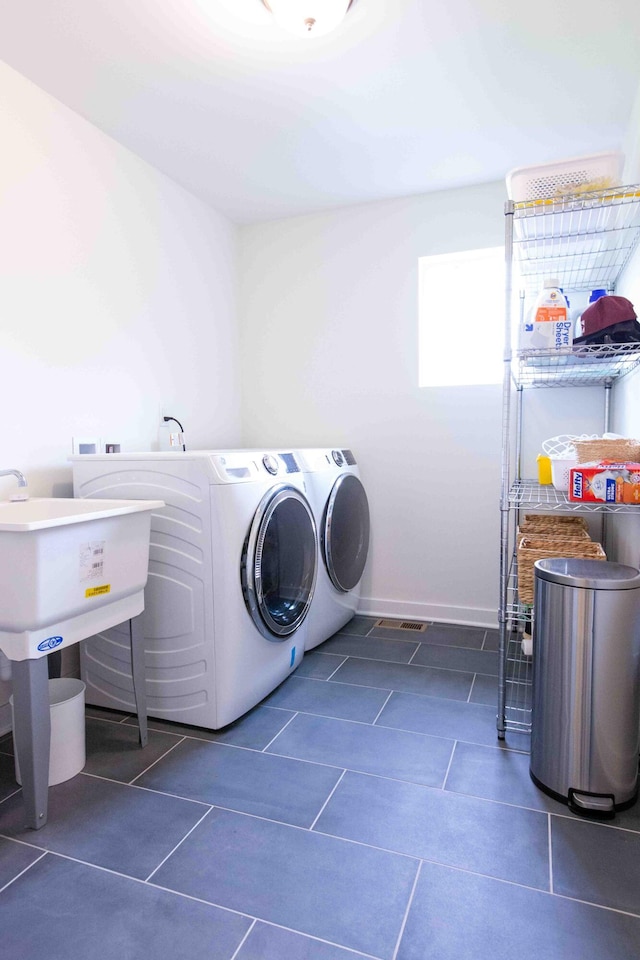 laundry room featuring dark tile patterned floors, baseboards, washing machine and dryer, and laundry area