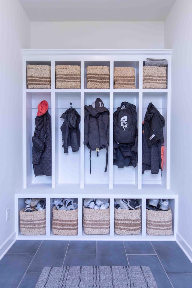 mudroom with baseboards and dark tile patterned floors