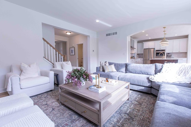 living room featuring stairway, recessed lighting, visible vents, and arched walkways