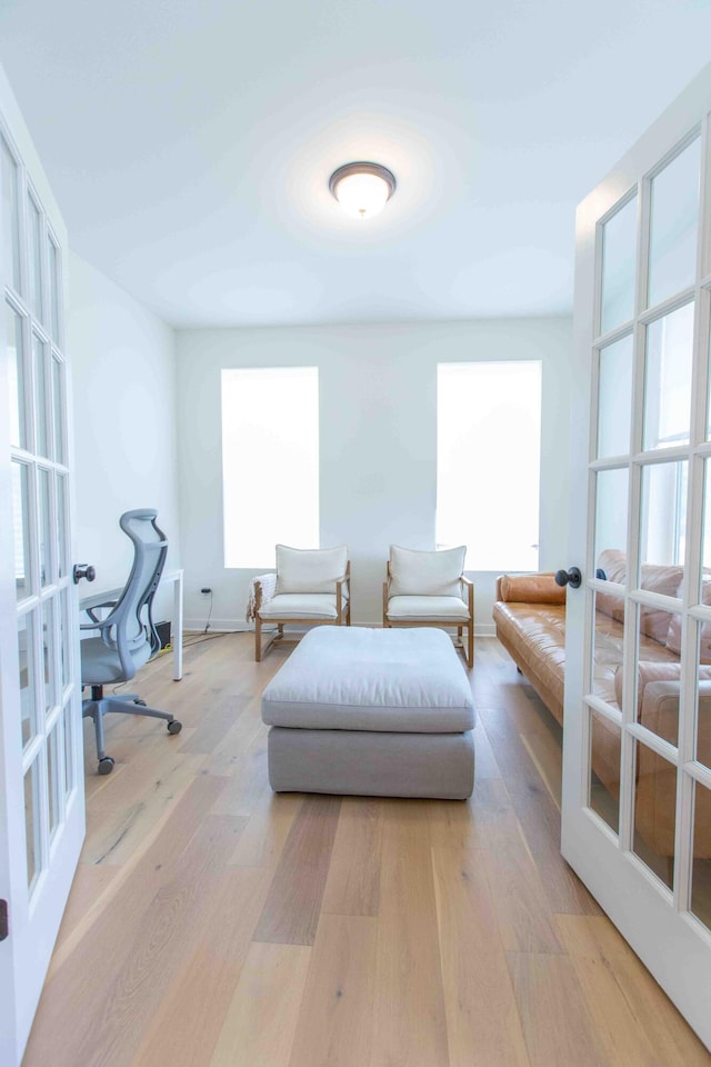 bedroom with multiple windows, french doors, and light wood-type flooring