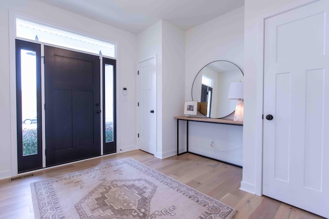 foyer featuring visible vents, baseboards, and wood finished floors