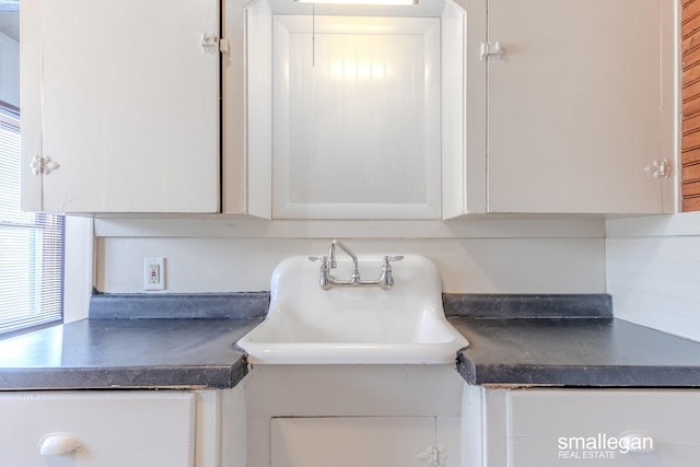 details featuring a sink, dark countertops, and white cabinets