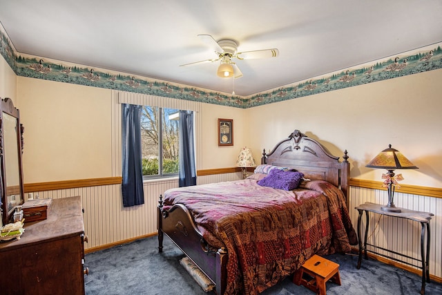 bedroom with baseboards, a wainscoted wall, carpet floors, and ceiling fan