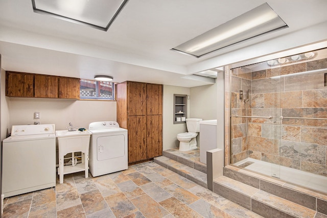 clothes washing area featuring stone tile flooring, a sink, and separate washer and dryer