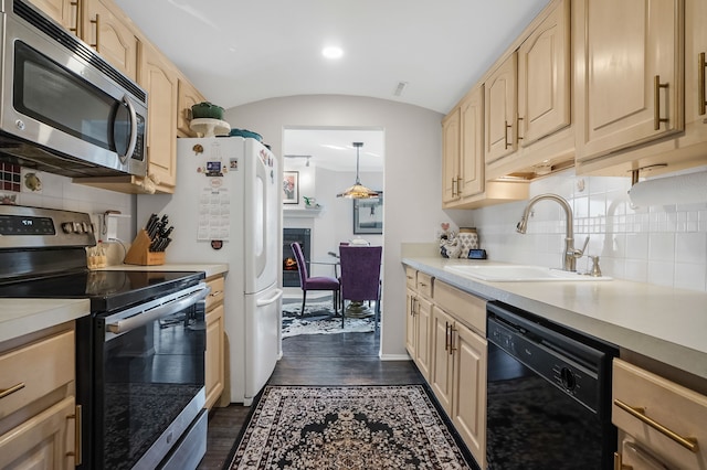 kitchen with light brown cabinets, a sink, dark wood-type flooring, vaulted ceiling, and appliances with stainless steel finishes