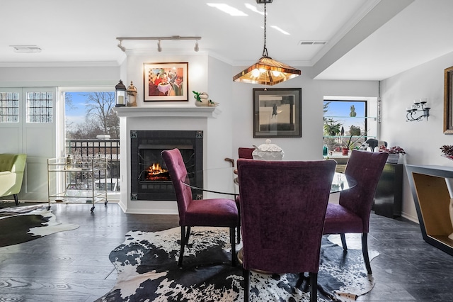 dining area featuring visible vents, a lit fireplace, wood finished floors, and crown molding