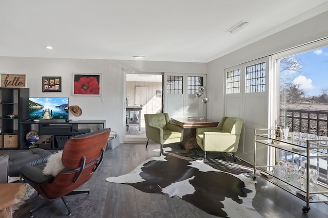 living area with visible vents, wood finished floors, and crown molding