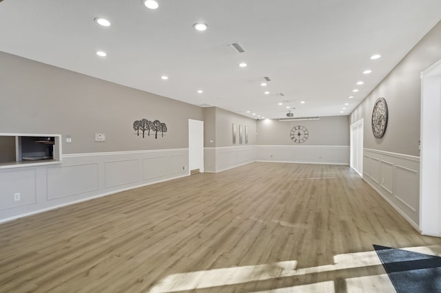 unfurnished living room featuring light wood-type flooring, visible vents, wainscoting, and recessed lighting