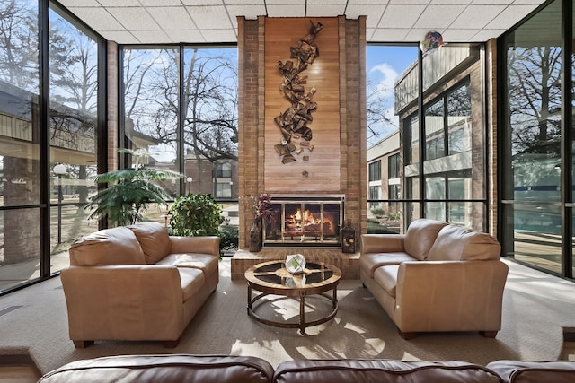 sunroom featuring a drop ceiling and a large fireplace