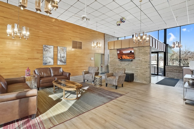 living area featuring a wall of windows, a notable chandelier, wood finished floors, and wooden walls