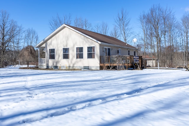 snow covered rear of property with a wooden deck