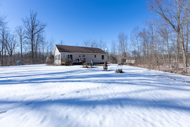 snow covered back of property featuring a deck