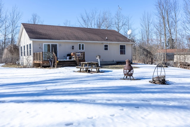 snow covered rear of property featuring a wooden deck and a shingled roof