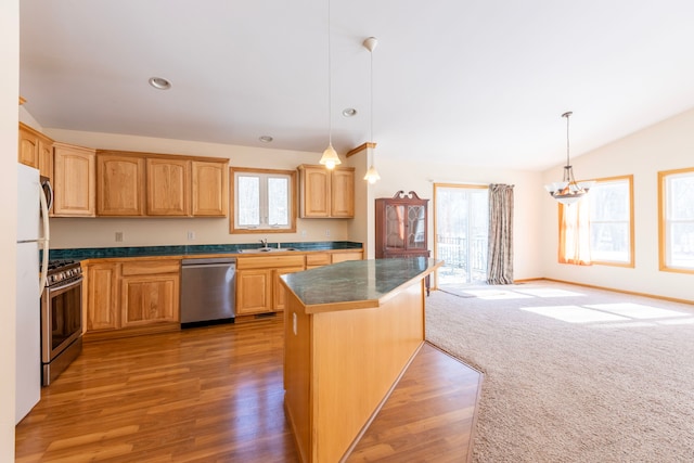 kitchen with lofted ceiling, a sink, hanging light fixtures, appliances with stainless steel finishes, and dark countertops