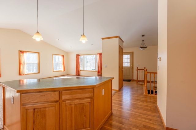 kitchen featuring baseboards, light wood-type flooring, lofted ceiling, and pendant lighting