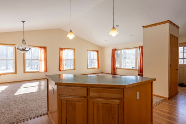 kitchen featuring hanging light fixtures, vaulted ceiling, open floor plan, and light wood-type flooring