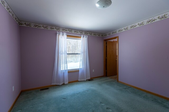 spare room with carpet flooring, visible vents, and baseboards