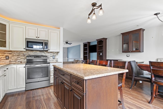 kitchen featuring backsplash, appliances with stainless steel finishes, a breakfast bar, and wood finished floors