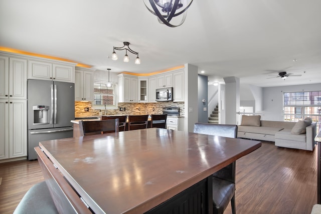 kitchen featuring dark wood-type flooring, a wealth of natural light, appliances with stainless steel finishes, and a center island