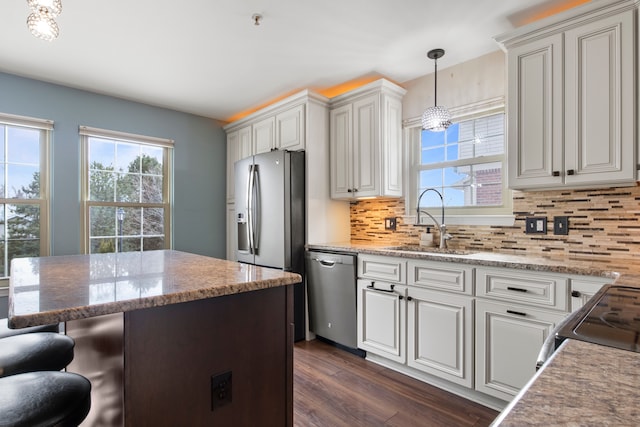 kitchen with tasteful backsplash, dark wood-type flooring, a breakfast bar, appliances with stainless steel finishes, and a sink