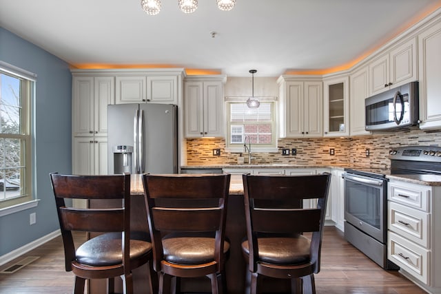 kitchen featuring decorative backsplash, appliances with stainless steel finishes, and dark wood-type flooring