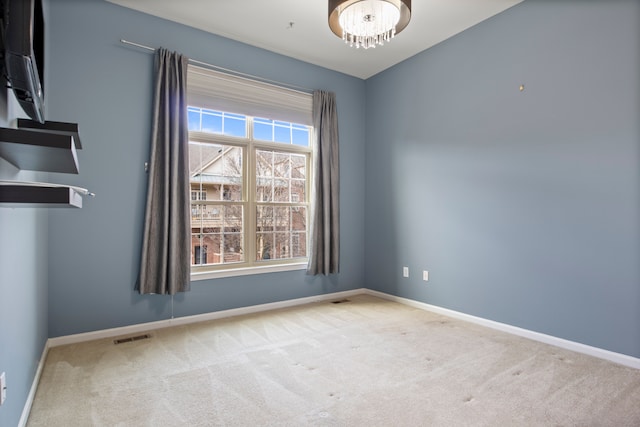 empty room with a notable chandelier, baseboards, carpet, and visible vents