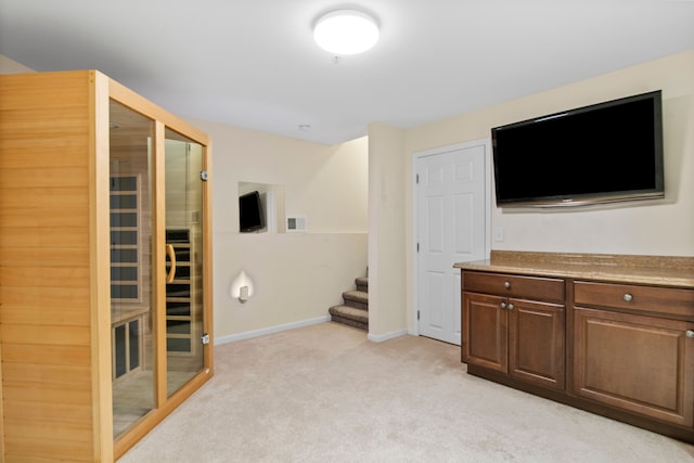 unfurnished living room with visible vents, a sauna, baseboards, light colored carpet, and stairs