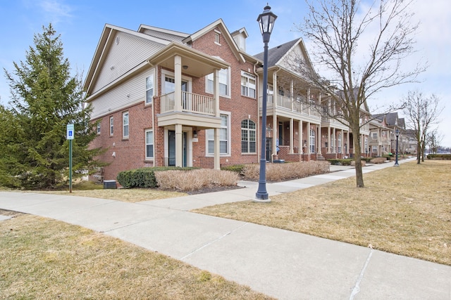 view of front of home with a residential view, brick siding, and a front lawn