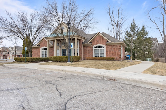 view of front facade with brick siding, a front lawn, and a shingled roof