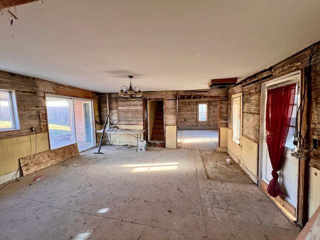 unfurnished living room featuring a wealth of natural light and a chandelier