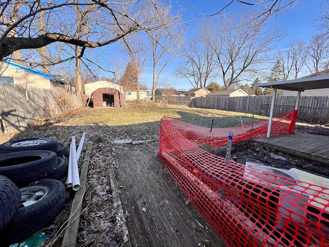 view of yard with an outbuilding, a storage unit, a fenced backyard, and a wooden deck