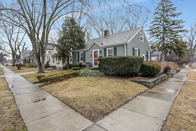 view of front of home featuring a front lawn, a chimney, and roof with shingles