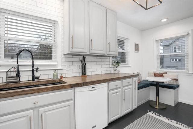 kitchen with white dishwasher, a sink, breakfast area, tasteful backsplash, and butcher block counters