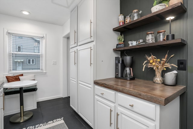 kitchen with open shelves, white cabinets, dark tile patterned floors, and breakfast area