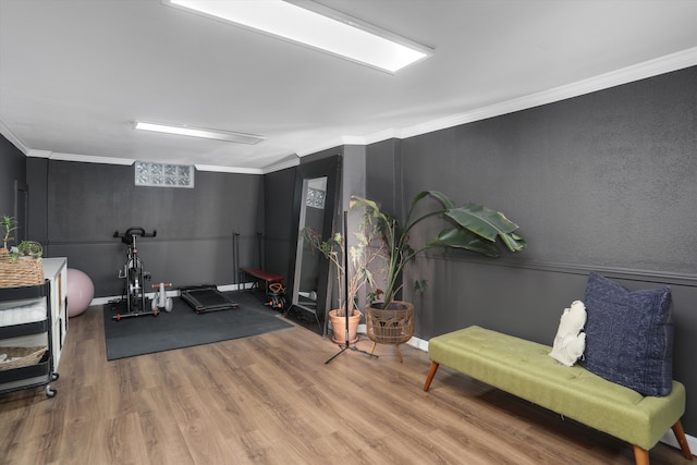 workout area with crown molding and wood finished floors