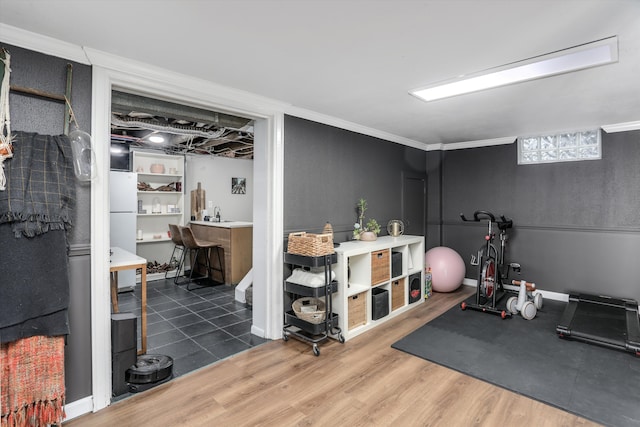 workout area with a bar, crown molding, and wood finished floors