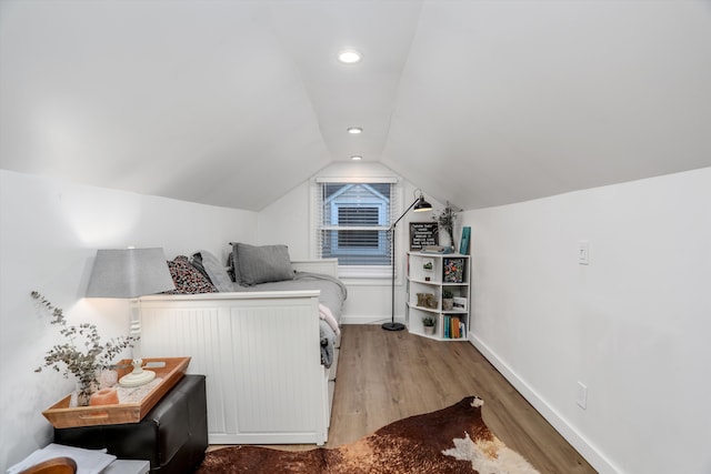 bedroom with baseboards, wood finished floors, and vaulted ceiling