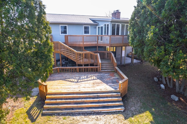 rear view of house with a wooden deck, stairway, a patio area, and a chimney