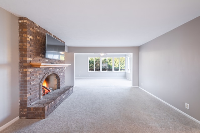 unfurnished living room featuring carpet flooring, a fireplace, and baseboards