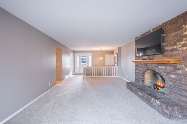 unfurnished living room with a brick fireplace, baseboards, and carpet