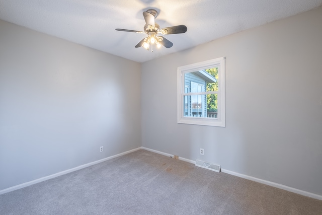 carpeted spare room featuring baseboards, visible vents, and ceiling fan